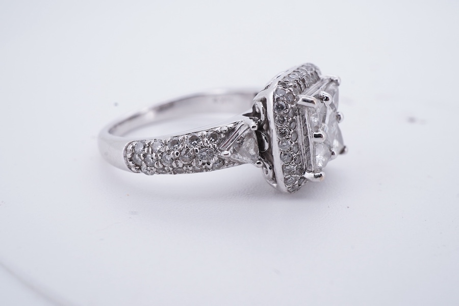 A diamond ring, centring on a tessellated arrangement of princess-cut and triangular diamonds totalling approximately 0.50 carats, to a border and band pavé-set with brilliant-cut diamonds, the shoulders accented with ad
